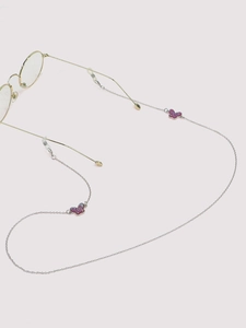 Detail of silver eyewear chain featuring pink butterfly charms on a soft pink background