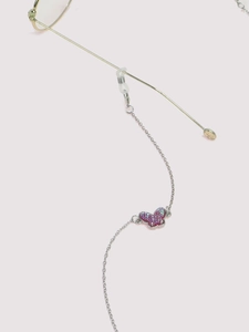 Detail of silver glasses chain with pink butterfly charm attached to gold frame temples