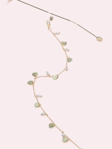 Detail of gold chain strap featuring white pearls and textured heart-shaped pendants