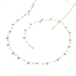 Detail of gold eyewear chain featuring shell charms and white imitation pearls on a fine link