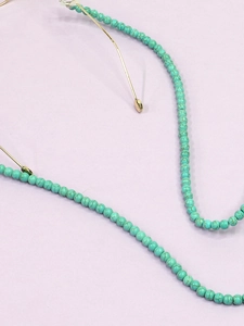 Détail de perles de turquoise 6mm avec maillons dorés sur une chaîne de lunettes