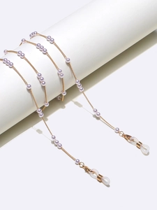 Vue détaillée d'une chaîne de lunettes dorée avec perles blanches sur support cylindrique