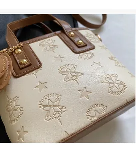 Détail du sac à main en cuir crème gaufré d'étoiles avec bordure marron et clous