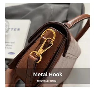 Close-up of premium golden metal hook and textured brown leather on a crossbody bag