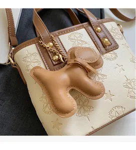 Détail du sac seau crème avec poignées marron et un pendentif mignon en forme de chien