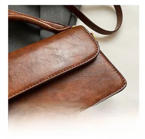 Close-up of vintage brown leather handbag with fine stitching and gold engraved logo