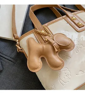 Détail du sac seau en cuir beige avec charme de chien 3D et motifs de dessins animés