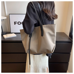 Détail d'un grand sac cabas kaki avec des bretelles noires porté par un mannequin chic