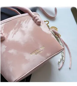 Detail der Handtasche mit rosa Marmormuster, Rundgriff und goldener Logogravur