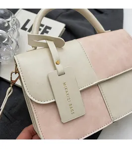 Detail of color-block leather handbag with litchi texture and metal strap hardware