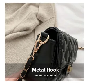 Detailed macro view of the golden metal hook and chain on a black quilted handbag