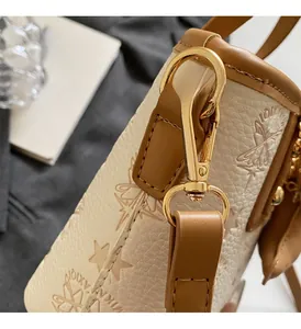Close-up of embossed cream leather handbag with gold metal hardware and star patterns
