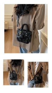 Détail d'un mini sac seau noir avec motifs logo et un adorable pendentif en forme d'ours