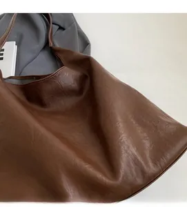 Gros plan montrant la texture douce et le grain naturel du sac cabas marron en similicuir