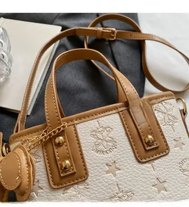 Detail view of the embossed star pattern and gold rivets on this beige bucket bag