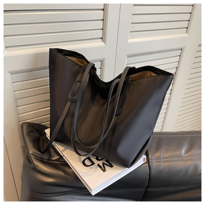 Détail d'un grand sac fourre-tout noir minimaliste avec texture lisse sur canapé