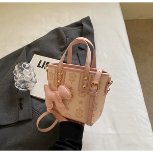 Rosa Eimertasche mit Sternmuster und Hundemanhänger auf weißer Oberfläche