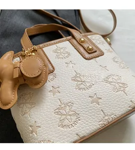 Detailed macro view of white lychee leather texture and star embossing on bucket bag