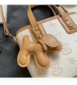 Detail of white bucket bag with brown trim featuring star embossing and puppy charm