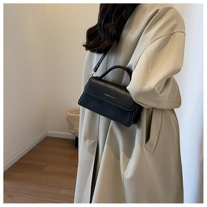 Chic black leather handbag with gold lettering shown on model for daily commute style