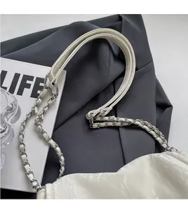 Detail of cream tote bag strap featuring interwoven silver chain and glossy leather texture