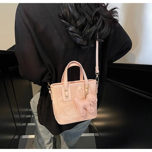Détails d'un mini sac seau rose avec gaufrage floral et breloque chiot élégante