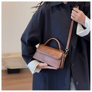 Close-up of brown vintage leather bag with gold metal buckle and adjustable shoulder strap