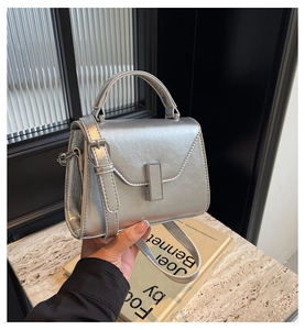 Détail d'un sac à main argenté avec fermoir métallique sur marbre et livres