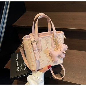 Détail du sac seau beige et rose avec gaufrage d'étoiles et breloque chien sur bois