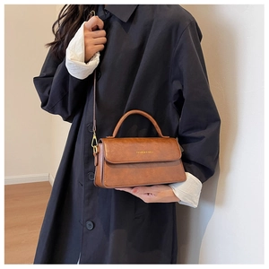 Detail view of the vintage brown leather crossbody bag with golden fashion lettering