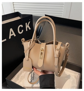 Close-up of beige lychee grain leather tote bag with gold metal lock and shoulder strap