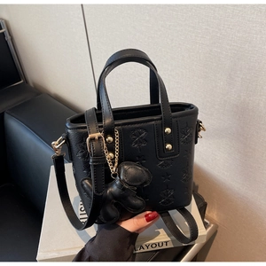 Détail d'un sac seau noir en cuir avec motifs étoiles gaufrés et pendentif chiot