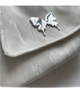 Close-up of white marble texture leather with metallic silver butterfly decoration