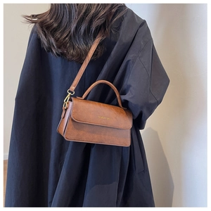 Detail of retro brown leather handbag with gold hardware and embossed lettering