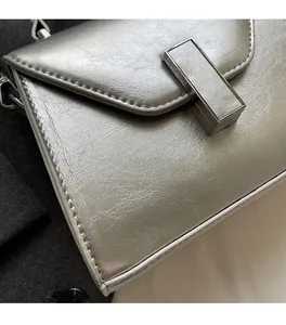 Détail macro de la texture cuir argenté nacré et de la boucle métallique sur le sac