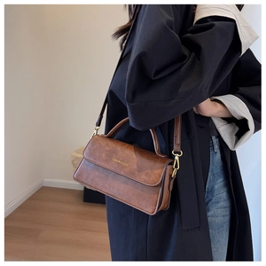 Detail of vintage brown leather handbag with gold hardware and embossed fashion text