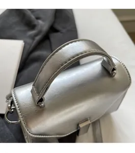 Vue détaillée de la poignée de sac à main argentée renforcée avec coutures et anneaux en métal