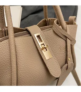 Close-up of khaki pebbled leather tote bag featuring a gold metal lock and zipper detail