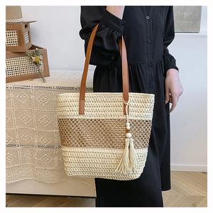 Detail of hand-woven straw tote with beige and brown contrast and wooden bead tassel