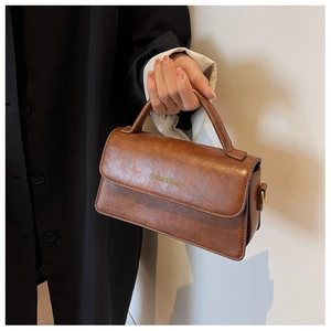 Detail of vintage brown textured leather handbag with gold logo and handle