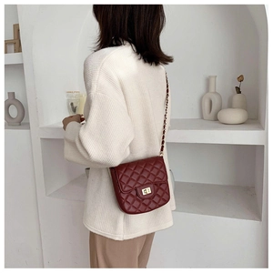 Detail of burgundy quilted crossbody bag with gold-tone twist lock and chain strap