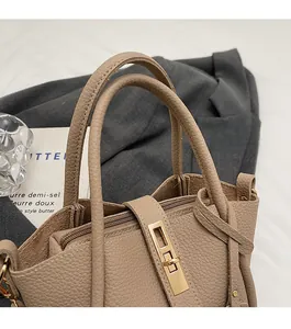 Close-up of khaki lychee grain leather bucket bag with gold twist lock and zipper detail