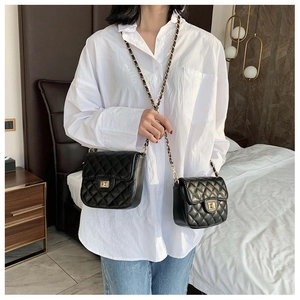 Detail of black quilted crossbody bags with gold chain strap and turn-lock closure