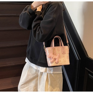 Detail der rosa geprägten Lederbeuteltasche mit Sternmuster und süßem Hundeanhänger