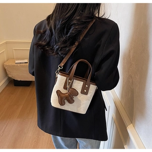 Détail du sac seau bandoulière tendance avec gaufrage papillon et breloque chien à l'épaule