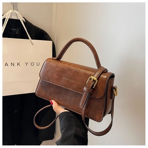 Detailed macro view of vintage brown leather handbag with gold metal clasp and top handle