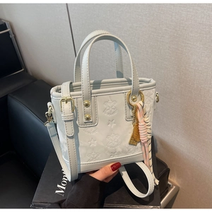 Dettaglio mini borsa azzurra con goffratura a stella e ciondolo a racchetta dorata