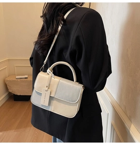 Detail of color-block mini handbag with top handle and strap shown on model's shoulder