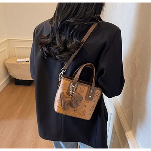 Détail du sac seau gaufré avec motifs d'étoiles et un pendentif de chien en cuir brun
