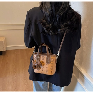 Detail der braunen Vintage-Eimertasche mit niedlichem Hundeanhänger am Modell